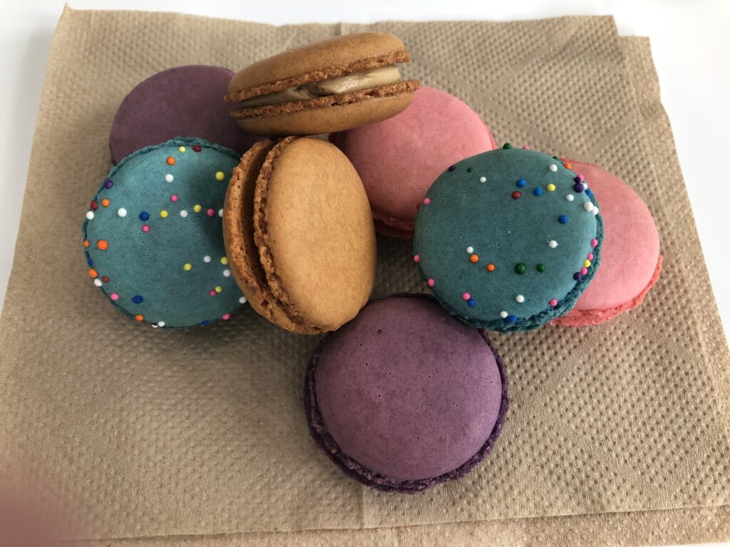A variety of brightly colored macaron cookies sit on a brown napkin